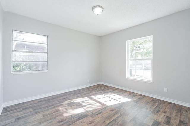 spare room featuring dark hardwood / wood-style floors and a textured ceiling