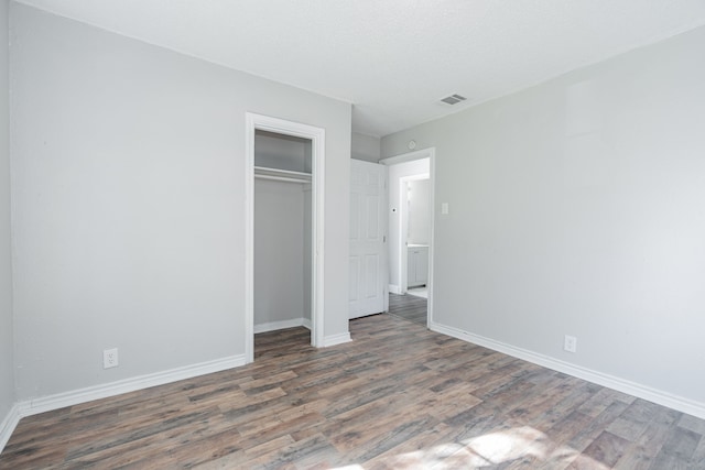 unfurnished bedroom with dark hardwood / wood-style flooring and a closet