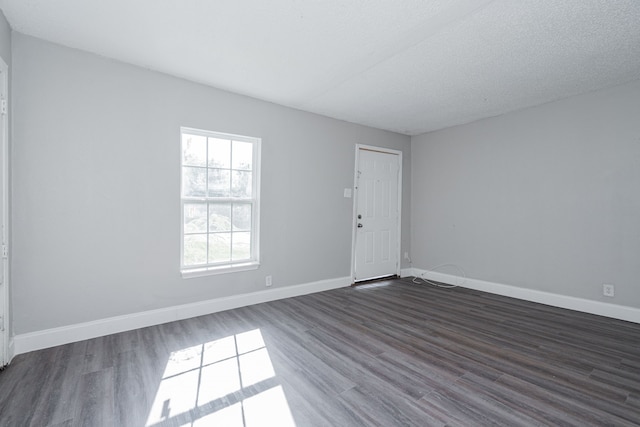 spare room with a textured ceiling and dark hardwood / wood-style flooring