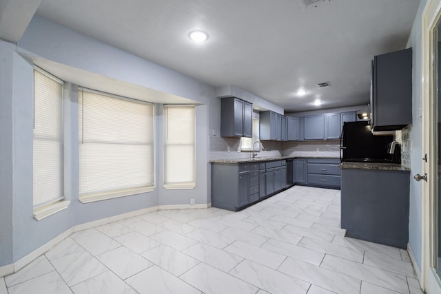 kitchen featuring gray cabinetry, decorative backsplash, sink, and fridge