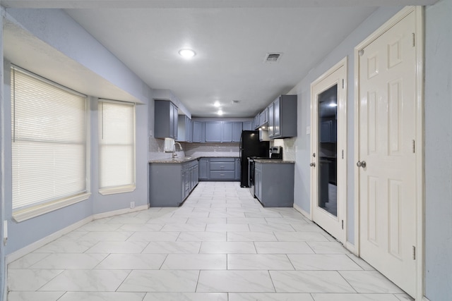 kitchen with gray cabinetry, decorative backsplash, sink, and stainless steel range with electric cooktop