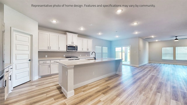 kitchen featuring white cabinetry, a center island with sink, ceiling fan, and sink