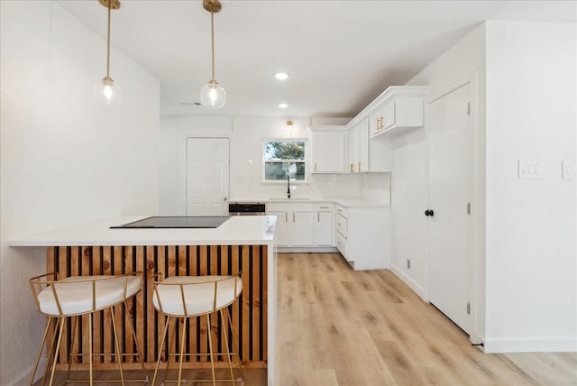 kitchen with pendant lighting, white cabinets, sink, light hardwood / wood-style flooring, and black electric cooktop