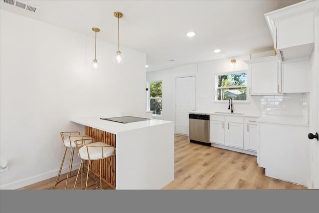 kitchen featuring light wood-type flooring, stainless steel dishwasher, sink, decorative light fixtures, and white cabinets