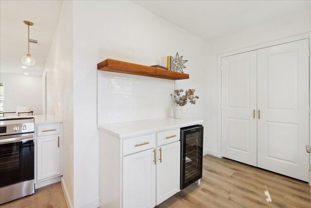 kitchen with wine cooler, stainless steel range, white cabinets, and light wood-type flooring