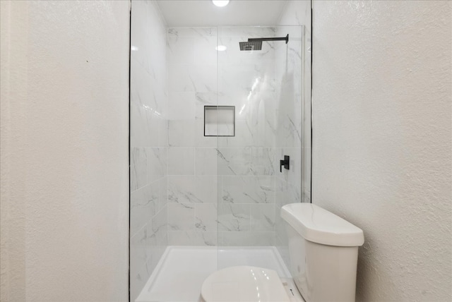 bathroom featuring a tile shower and toilet