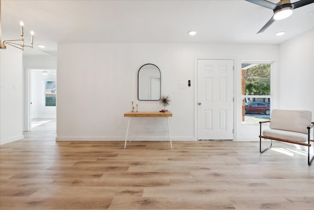 foyer entrance with light hardwood / wood-style flooring and ceiling fan with notable chandelier