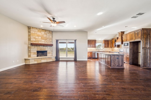 kitchen featuring ceiling fan, appliances with stainless steel finishes, tasteful backsplash, a kitchen island, and dark hardwood / wood-style flooring