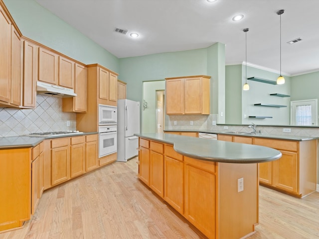 kitchen with a kitchen island, light wood-type flooring, white appliances, and ornamental molding