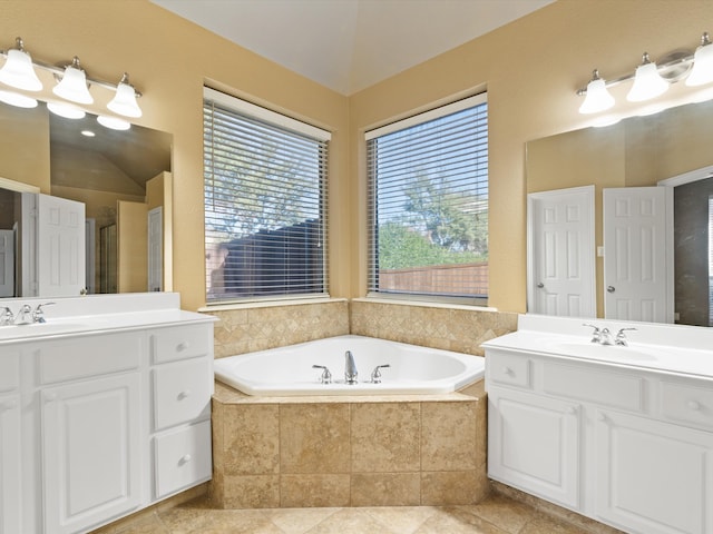 bathroom with tile patterned floors, tiled tub, and vanity