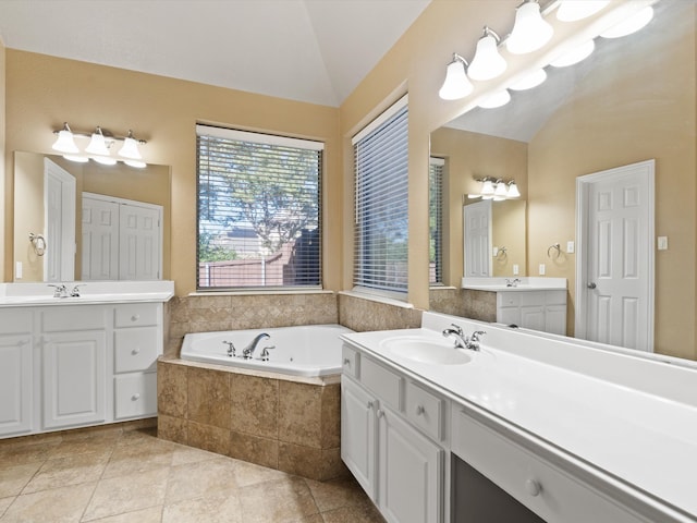 bathroom featuring tile patterned floors, vanity, vaulted ceiling, and tiled tub