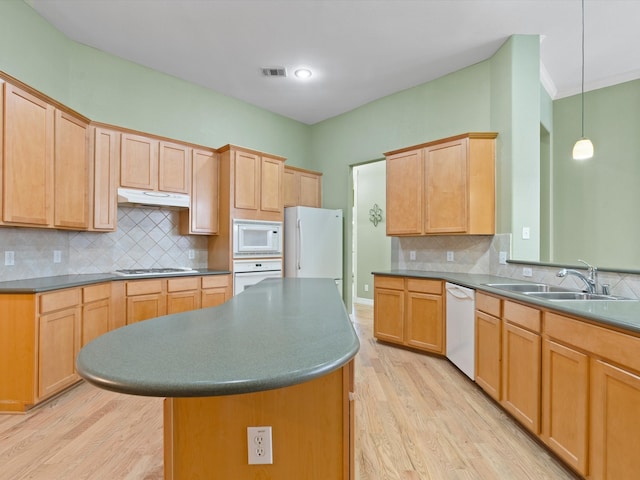 kitchen with sink, backsplash, white appliances, a kitchen island, and light wood-type flooring