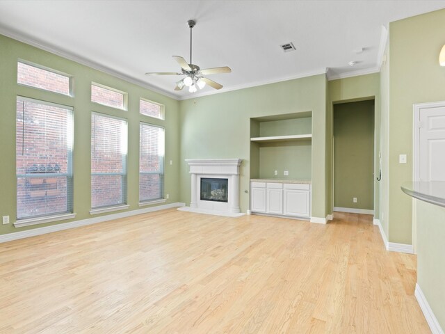 unfurnished living room featuring ceiling fan, light hardwood / wood-style floors, built in features, and crown molding