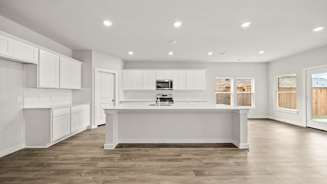 kitchen featuring an island with sink, dark hardwood / wood-style floors, sink, and white cabinets