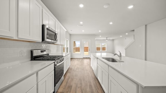 kitchen featuring white cabinetry, appliances with stainless steel finishes, and a center island with sink