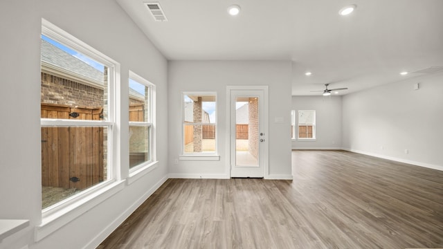 unfurnished living room featuring hardwood / wood-style flooring, ceiling fan, and plenty of natural light