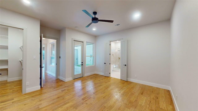 unfurnished bedroom featuring ceiling fan, a walk in closet, light hardwood / wood-style flooring, and ensuite bath