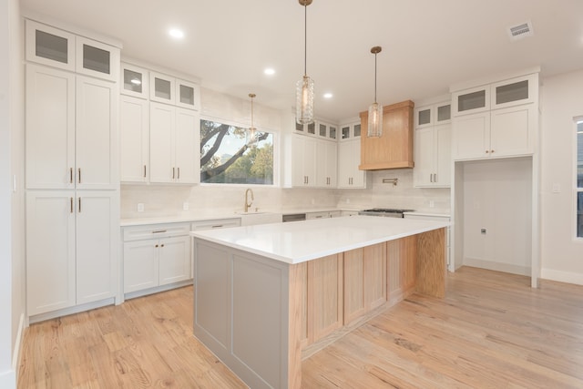 kitchen featuring white cabinets, sink, a kitchen island, and light hardwood / wood-style floors