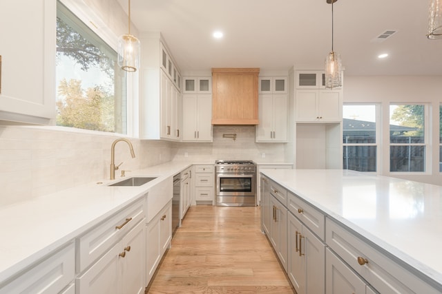 kitchen featuring stainless steel appliances, white cabinetry, hanging light fixtures, and sink