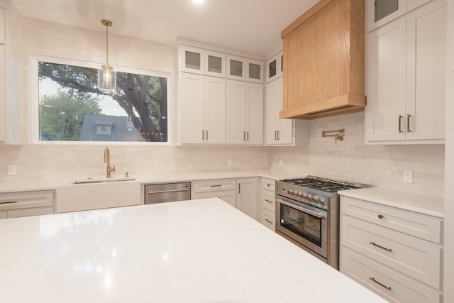 kitchen featuring decorative backsplash, stainless steel appliances, sink, decorative light fixtures, and white cabinets