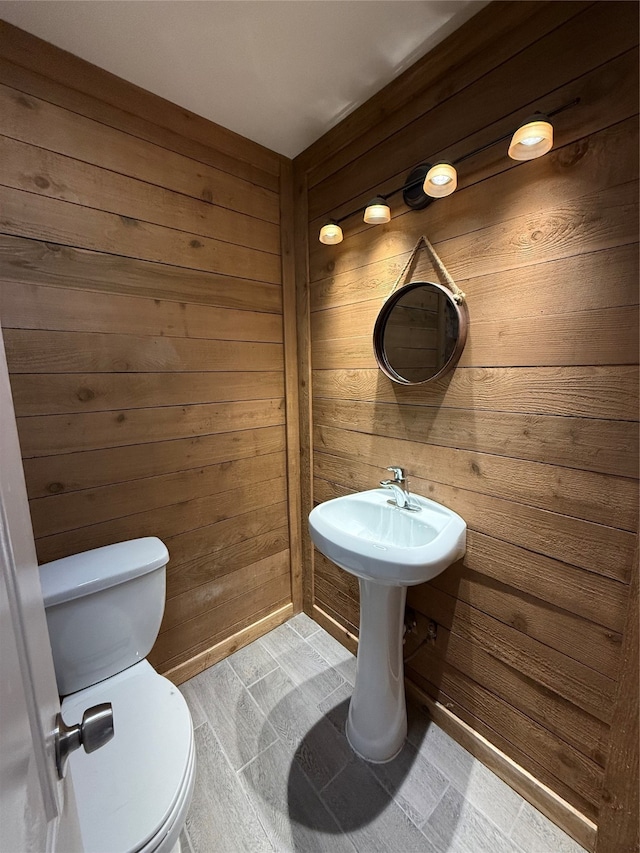 bathroom featuring wood walls and toilet