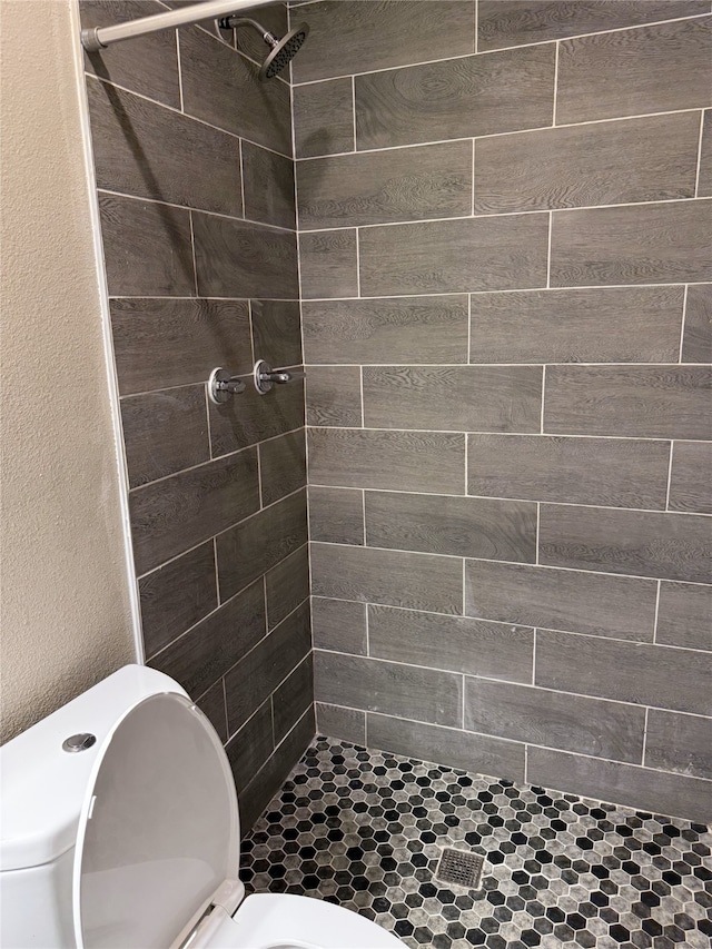 bathroom with tiled shower and toilet