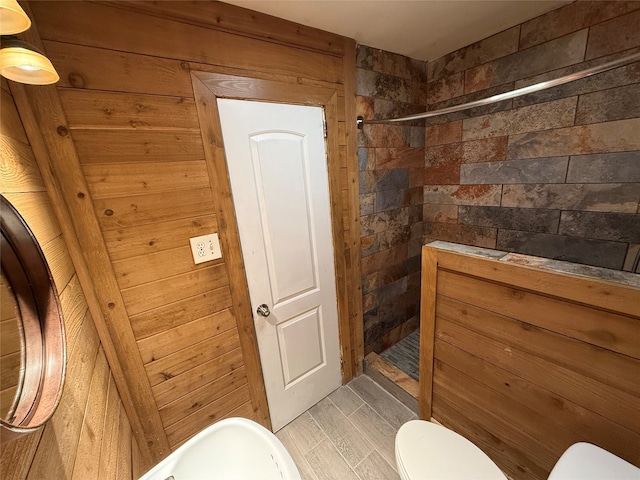 bathroom featuring toilet, walk in shower, and wood walls