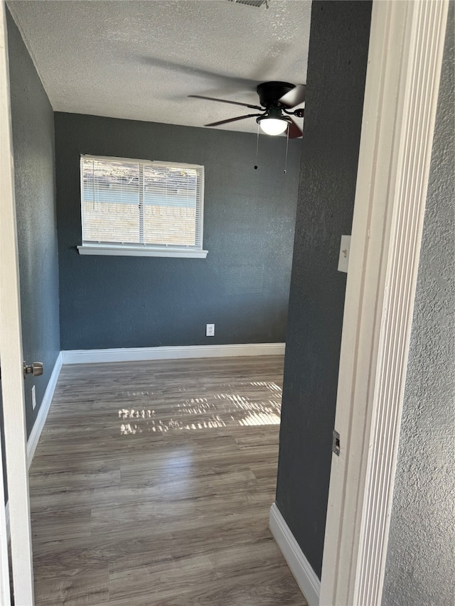 spare room with hardwood / wood-style flooring, ceiling fan, and a textured ceiling