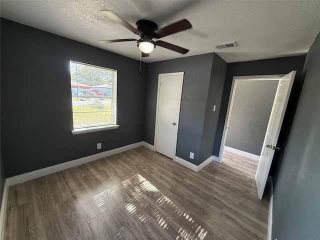 unfurnished bedroom with hardwood / wood-style flooring, ceiling fan, and a textured ceiling