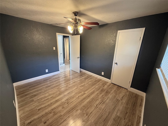 unfurnished room with a textured ceiling, light hardwood / wood-style floors, and ceiling fan