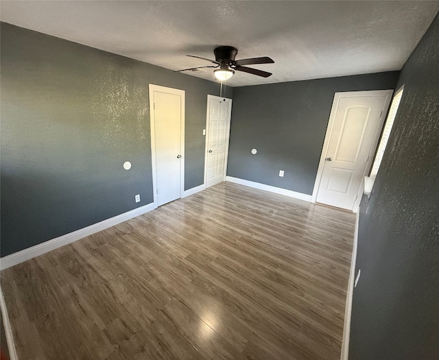 unfurnished bedroom with wood-type flooring, a textured ceiling, and ceiling fan