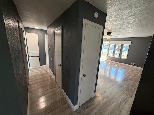 hallway with a textured ceiling and hardwood / wood-style flooring