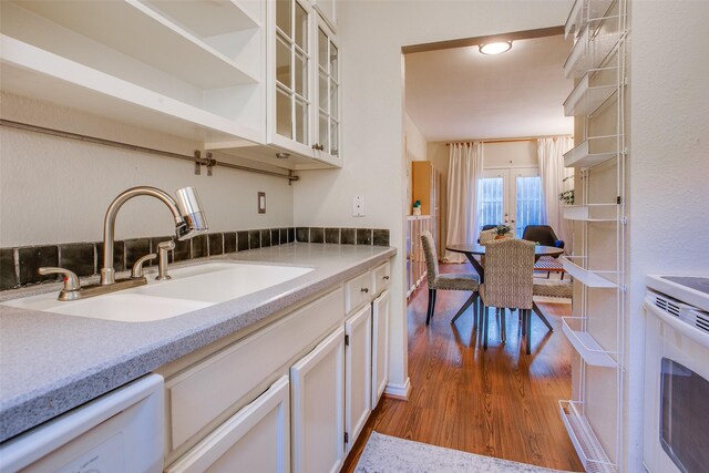 kitchen with white cabinetry, sink, dark hardwood / wood-style flooring, white dishwasher, and stainless steel stove