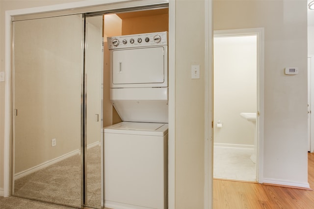 washroom featuring light hardwood / wood-style floors and stacked washing maching and dryer