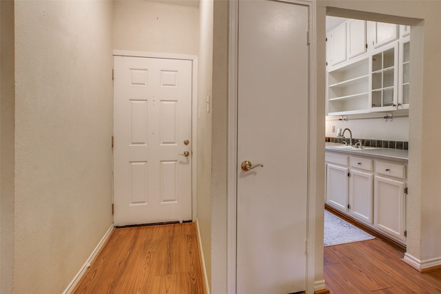 corridor with light hardwood / wood-style flooring and sink