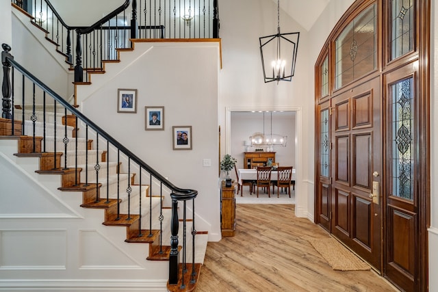 entryway with a towering ceiling, an inviting chandelier, and light hardwood / wood-style flooring