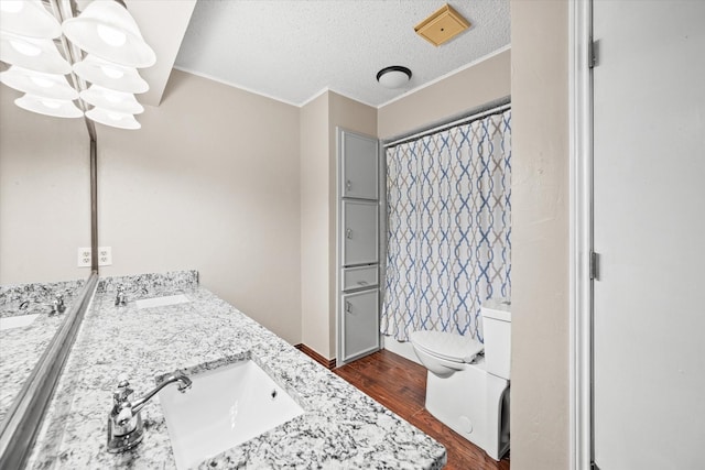 bathroom with hardwood / wood-style flooring, vanity, toilet, and a textured ceiling