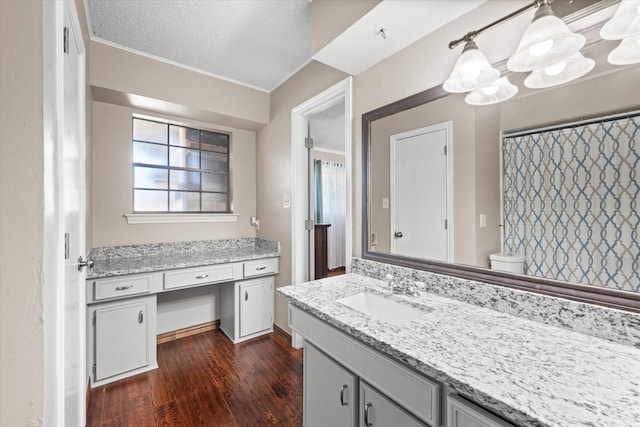 bathroom featuring a textured ceiling, vanity, crown molding, hardwood / wood-style flooring, and toilet