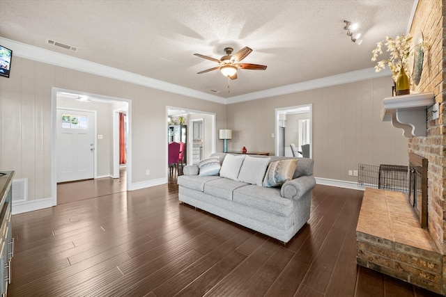 living room with a fireplace, crown molding, dark hardwood / wood-style flooring, and ceiling fan