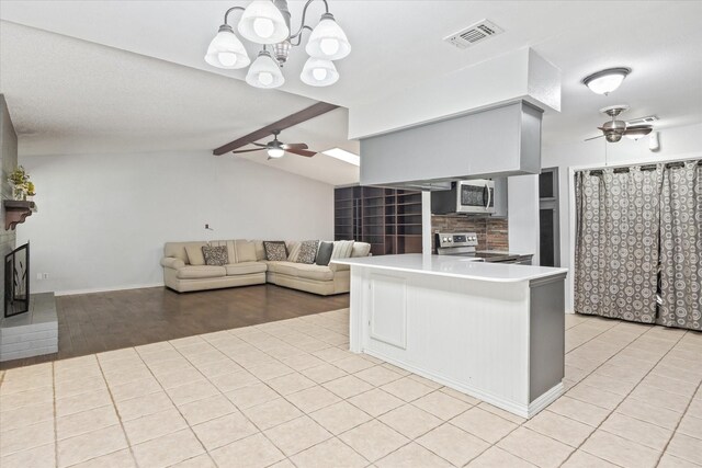 kitchen featuring lofted ceiling with beams, ceiling fan with notable chandelier, light hardwood / wood-style flooring, appliances with stainless steel finishes, and kitchen peninsula