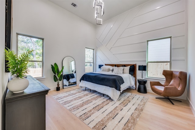 bedroom featuring a high ceiling and light hardwood / wood-style floors