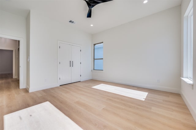 unfurnished bedroom featuring ceiling fan, light wood-type flooring, and a closet