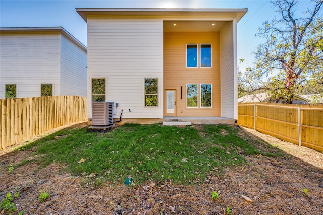 back of property with a yard and central AC