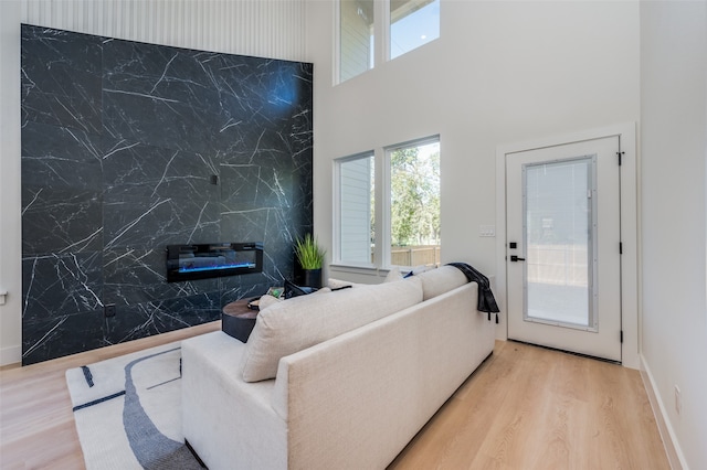 living room featuring light hardwood / wood-style floors, a premium fireplace, tile walls, and a high ceiling