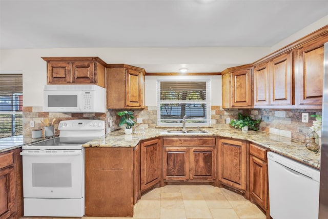 kitchen with a healthy amount of sunlight, white appliances, sink, and tasteful backsplash