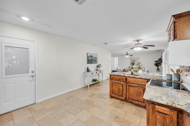 kitchen featuring light stone counters, stove, and ceiling fan