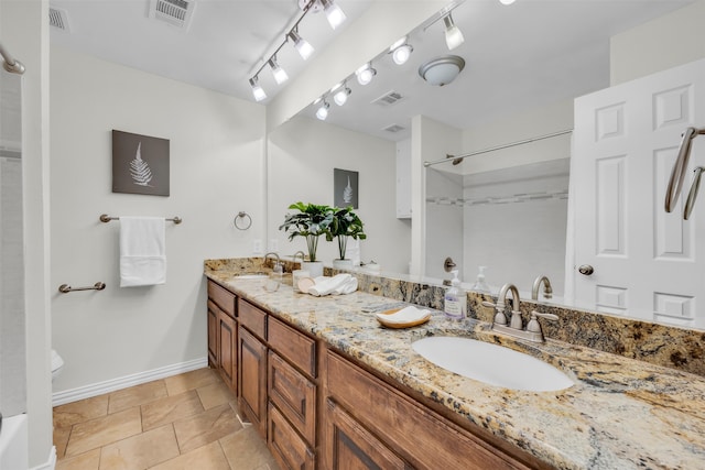 bathroom with toilet, vanity, track lighting, and tile patterned floors