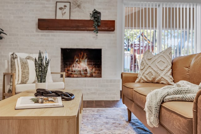 living room with a fireplace, a healthy amount of sunlight, brick wall, and wood-type flooring