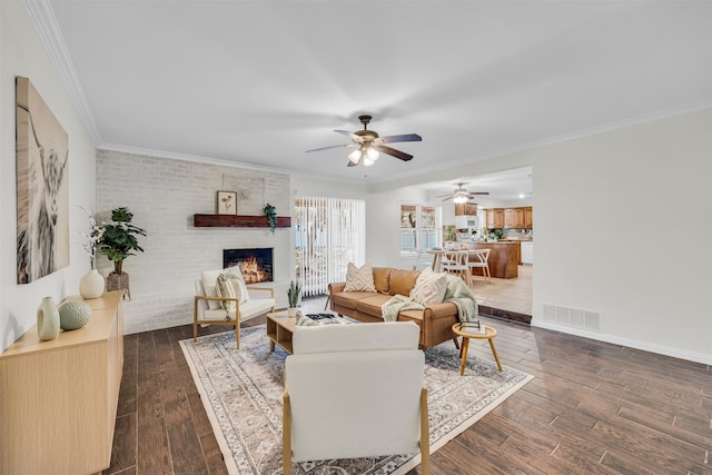 living room featuring dark hardwood / wood-style flooring, a brick fireplace, brick wall, ceiling fan, and crown molding