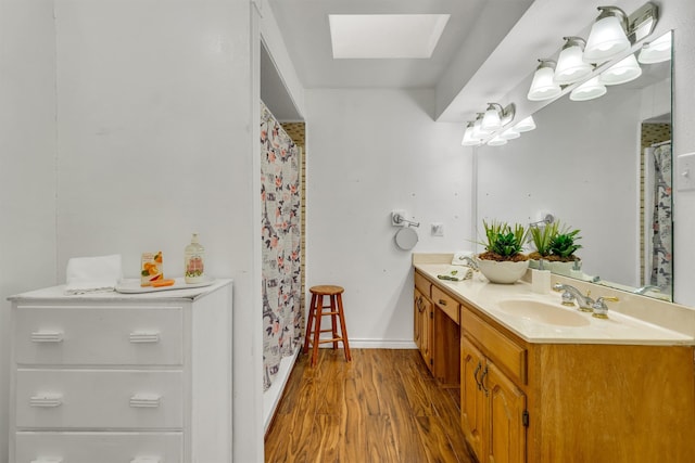 bathroom featuring a shower with shower curtain, hardwood / wood-style floors, vanity, and a skylight